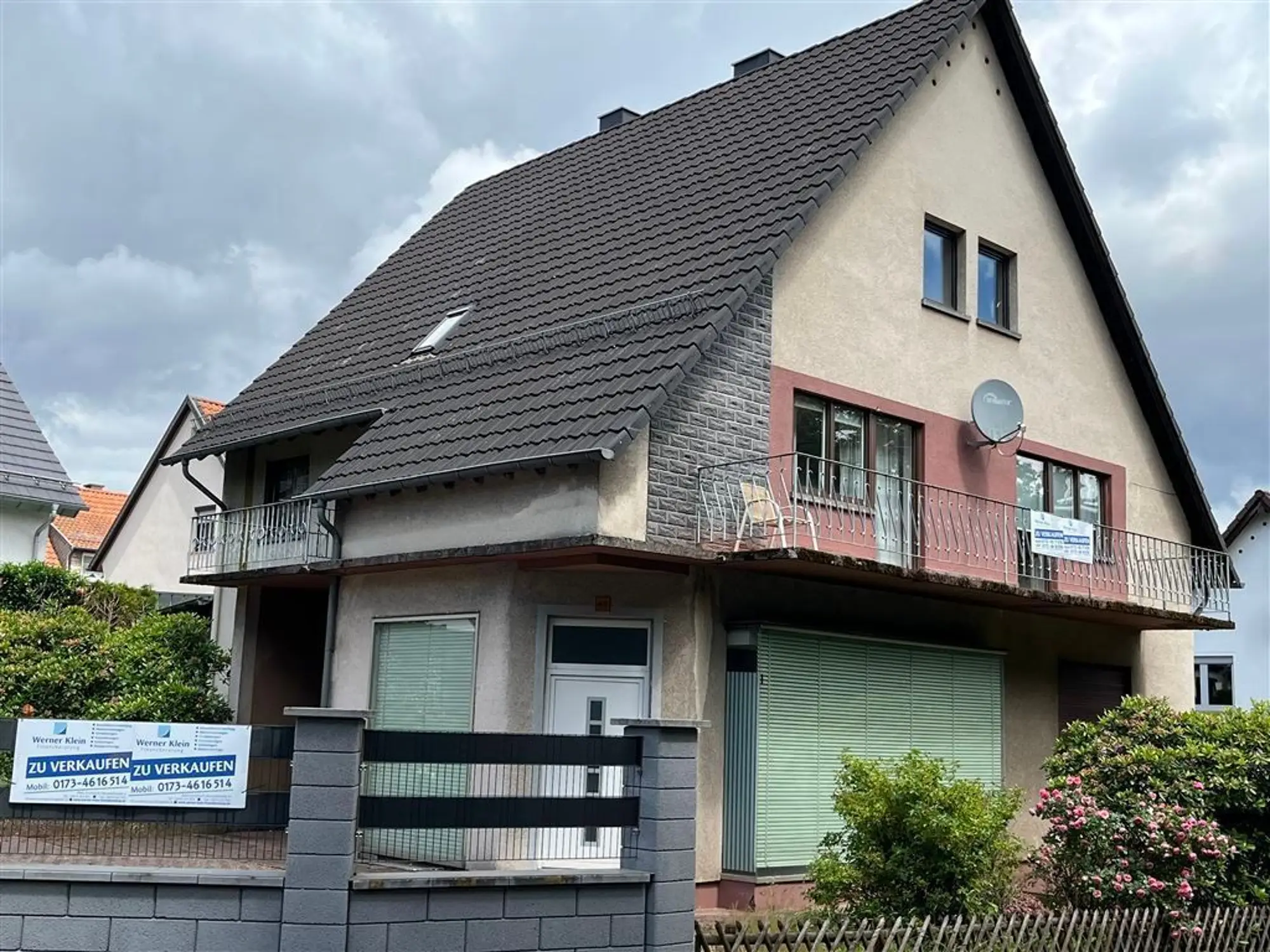 Straßenansicht des Einfamilienhauses mit Balkon und Verkaufsschild von Werner Klein Immobilien